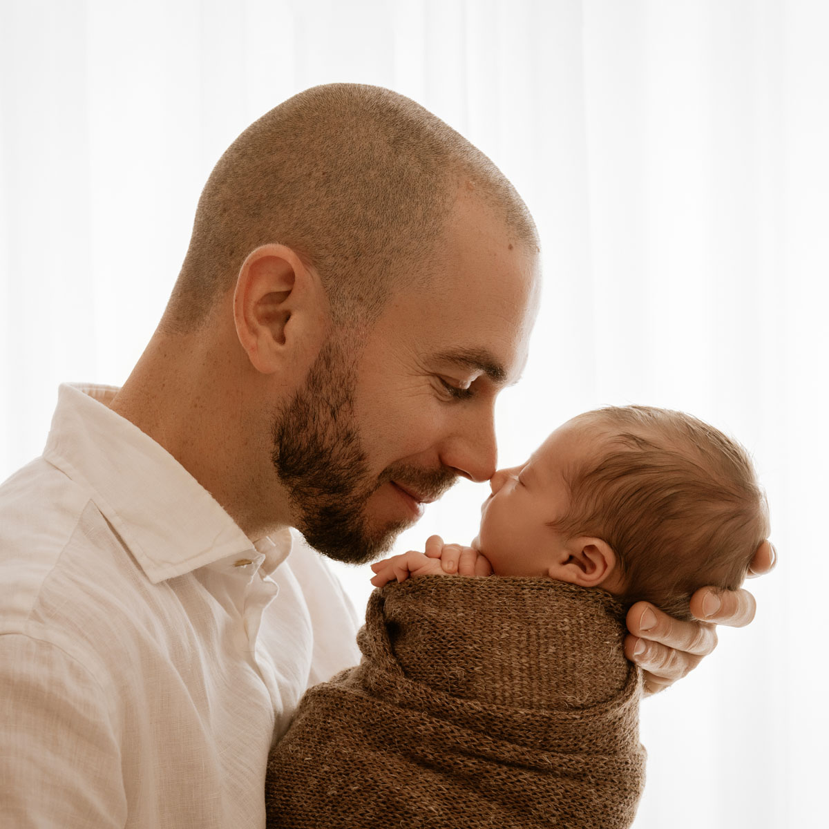 Papa berührt sein Neugeborenes sanft mit der Nase