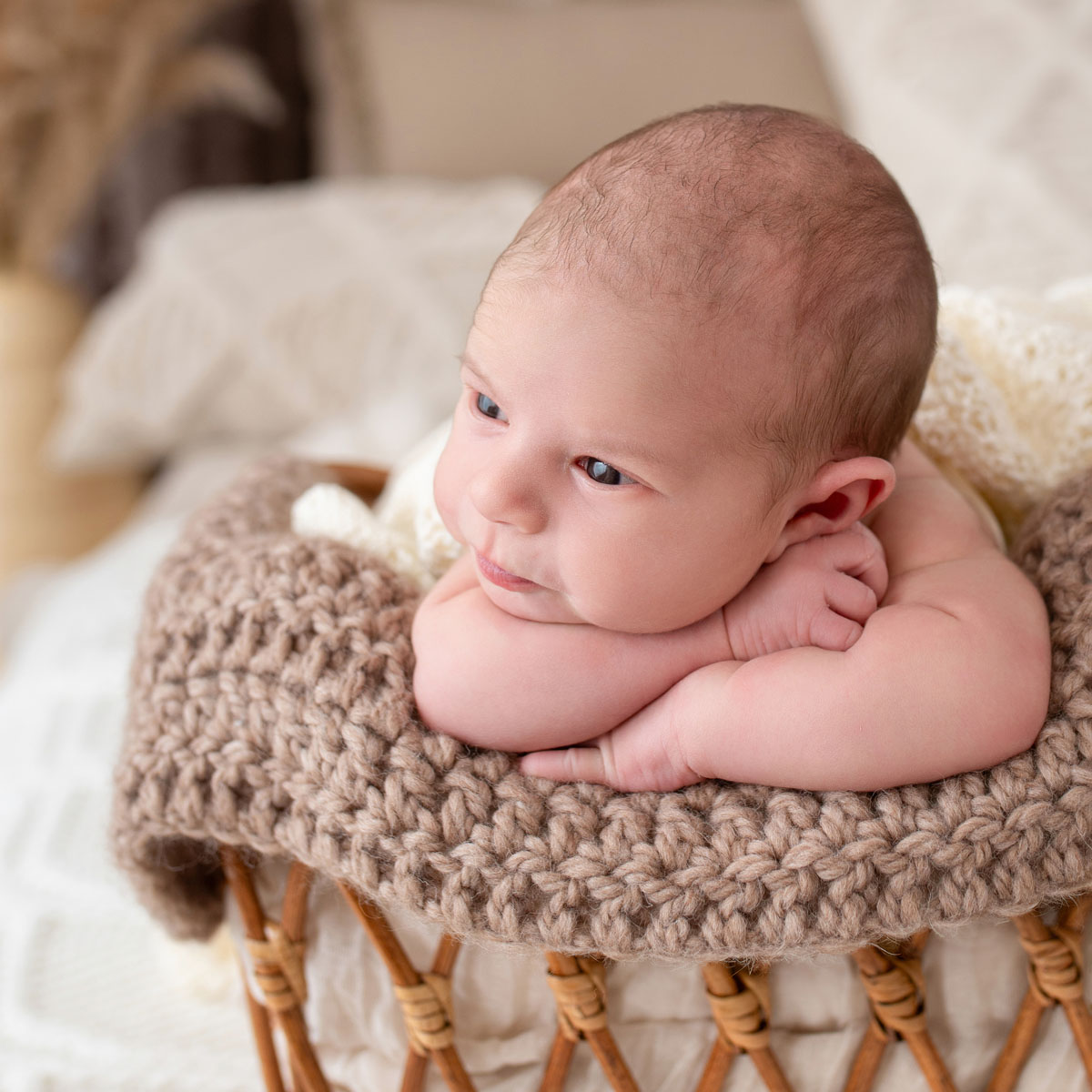 Baby stützt den Kopf auf die Arme in einem Körbchen