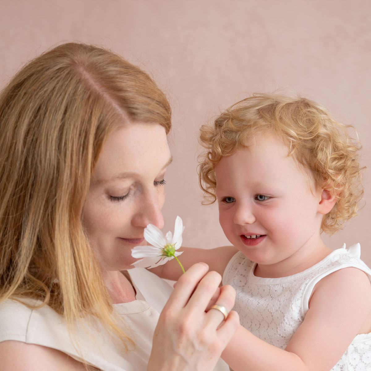 Mama und Tochter riechen an einer kleinen Blume