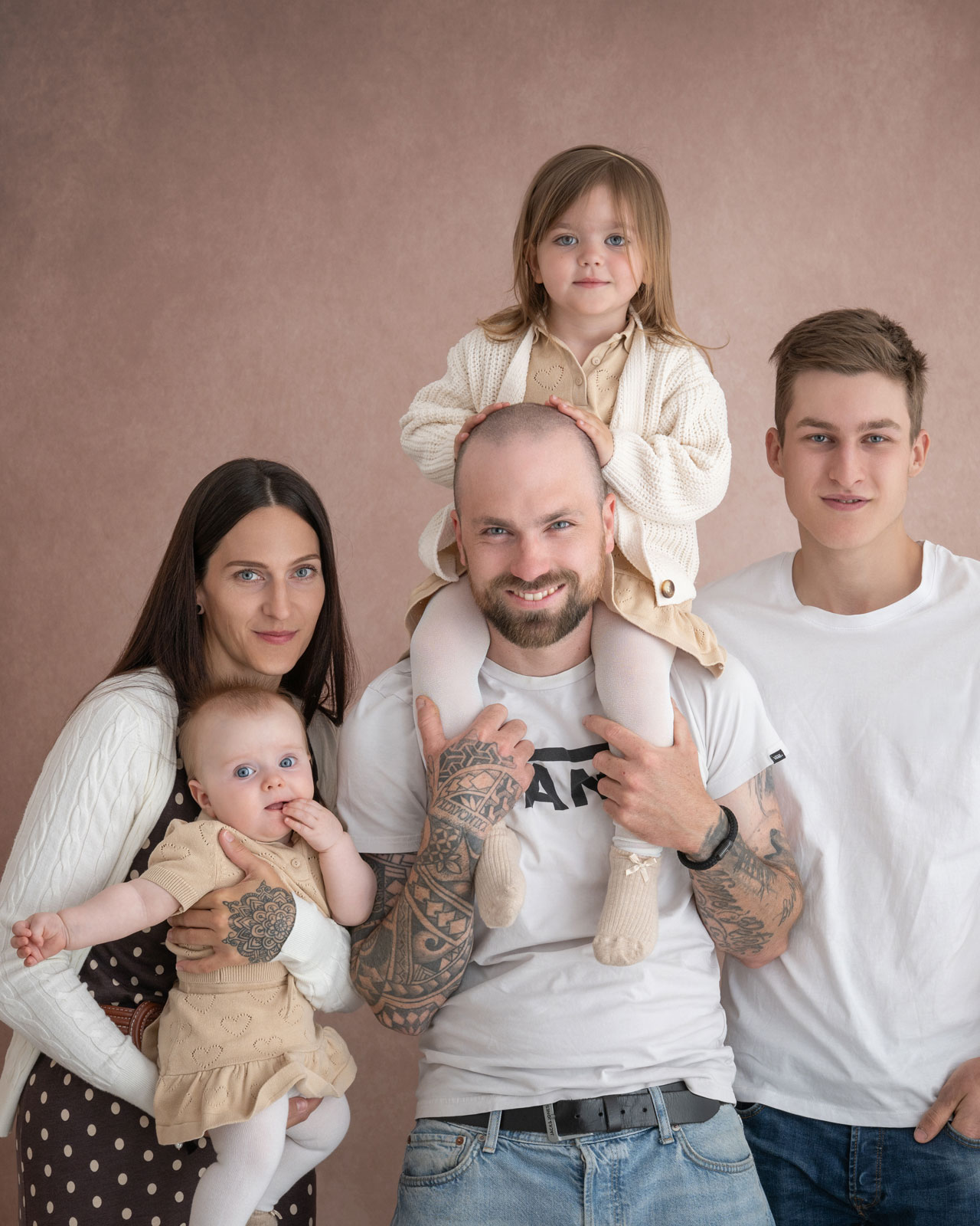 Familie mit drei Kindern, die Tochter sitzt auf Papas Schultern