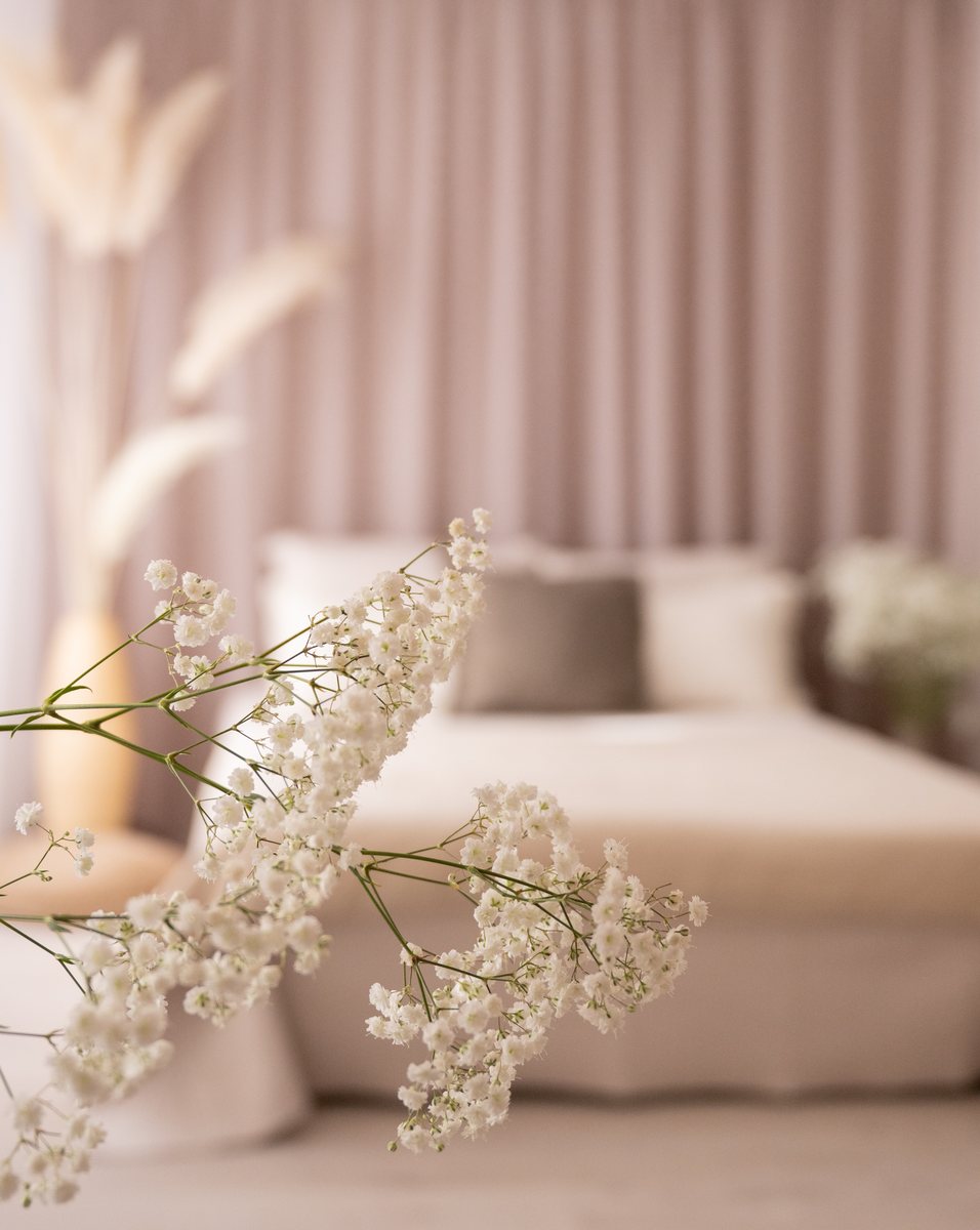 Blick durch zarte Blüten auf das Bett im Studio