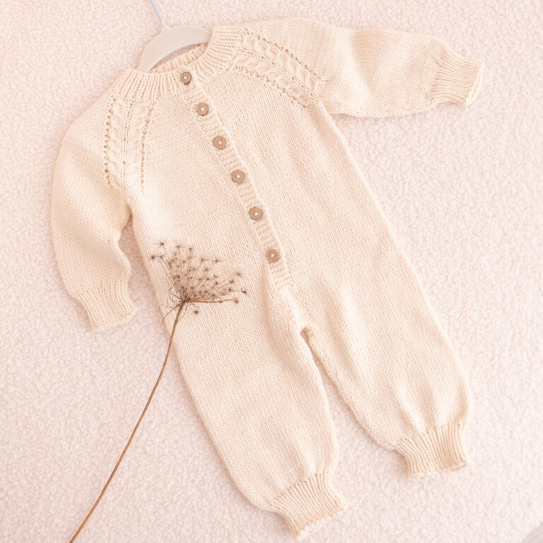 Handgestrickter Baby-Overall in Cremeweiß mit Zopfdetail und Holzknöpfen
